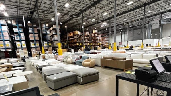 Warehouse-style discount furniture outlet filled with sofas, sectionals, and ottomans at clearance prices