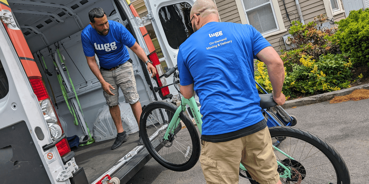Two professional Lugg movers loading a mint green bicycle into a delivery van for same-day transport.
