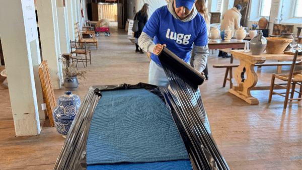Lugg mover wrapping antique furniture with moving blankets at Sylvie Estate Sale in Newburgh NY