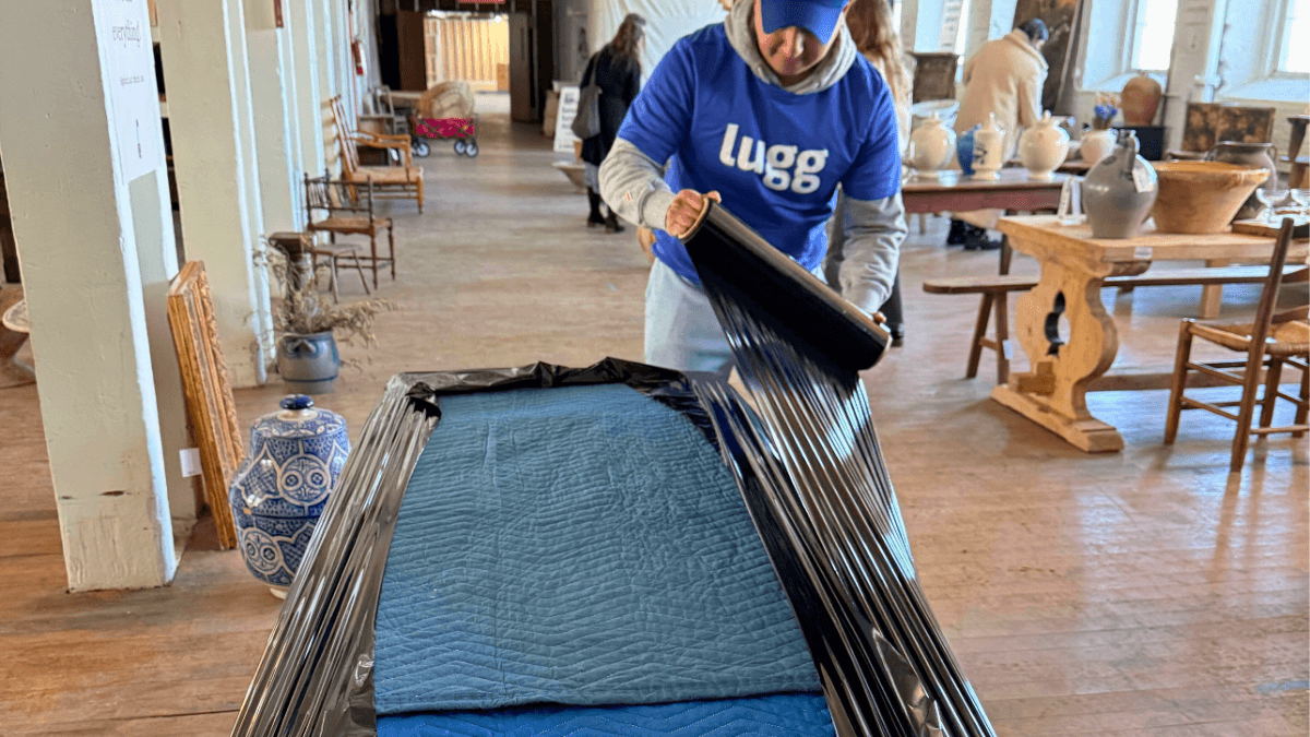 Lugg mover wrapping antique furniture with moving blankets at Sylvie Estate Sale in Newburgh NY
