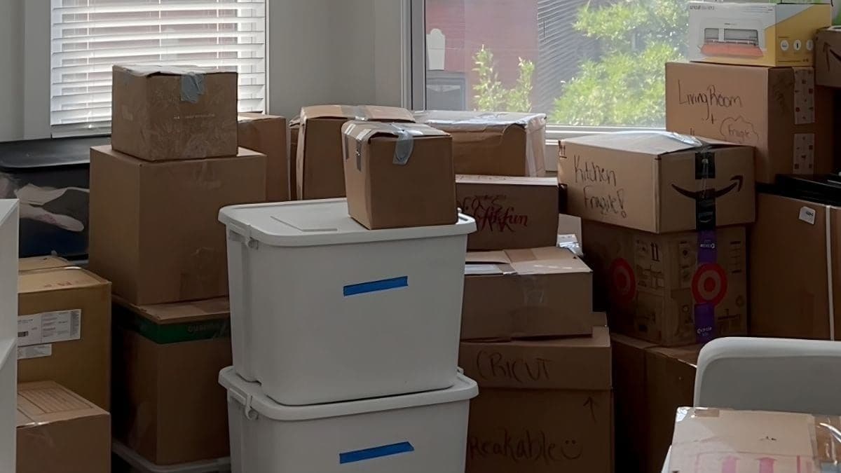 A room stacked with labeled moving boxes mid-move, including kitchen, living room, and fragile items ready for transport.