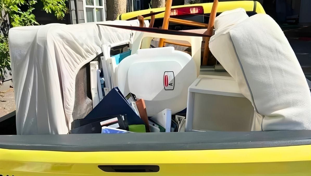 Lugg pickup truck loaded with a mattress, old furniture, chairs, and household junk during a junk removal job