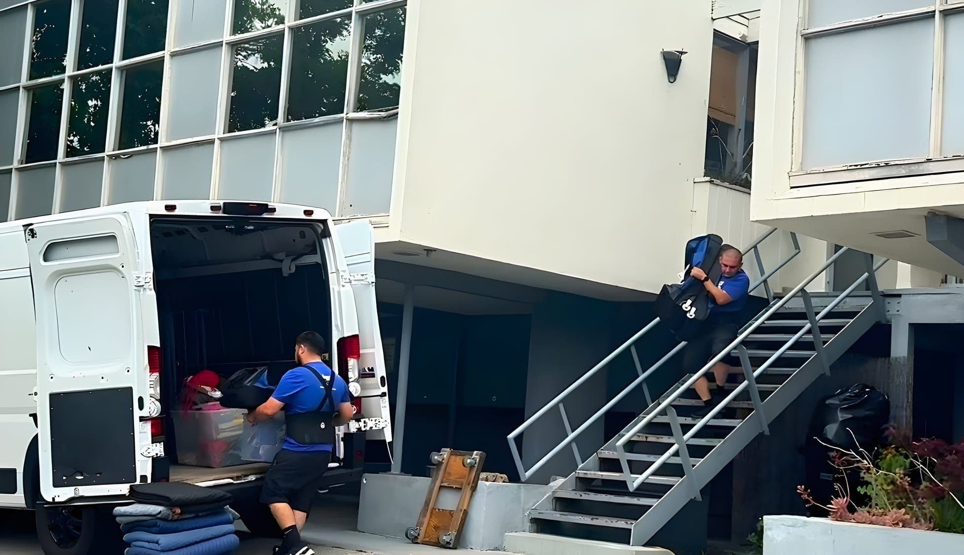 Two Lugg movers loading a cargo van with bins and moving blankets while carrying items up exterior stairs during a local commercial move