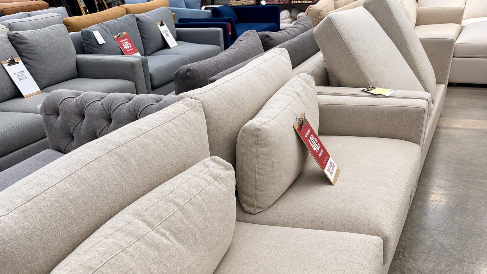 Sofas and armchairs in a furniture store with 40% off sale tags.