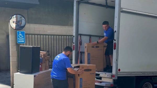 A Lugg 2-Lugger crew loads wardrobe boxes into a box truck — a typical on-demand box truck driver job in a city loading dock.