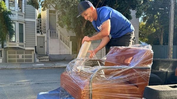 Uber for movers in action: a Lugg mover stretch-wrapping a leather armchair on a pickup truck during a residential San Francisco furniture move.