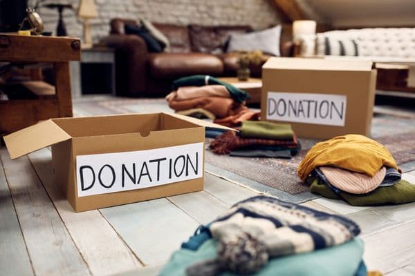 Boxes labeled "Donation" being filled with folded clothes while decluttering a home before a move